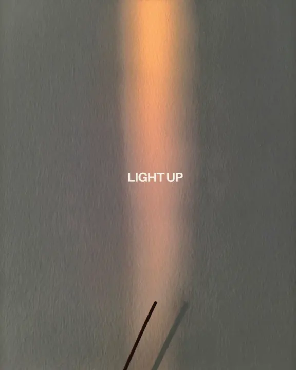 A lit incense stick against a warm beam of light